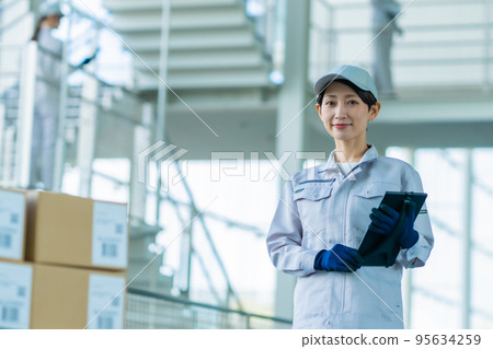 A staff member holding a tablet terminal and carrying out a shipping inspection 95634259