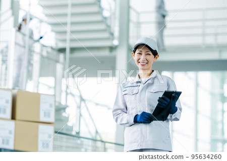 A staff member holding a tablet terminal and carrying out a shipping inspection 95634260