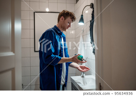 Man in dark-blue shirt in the bathroom washing hands 95634936