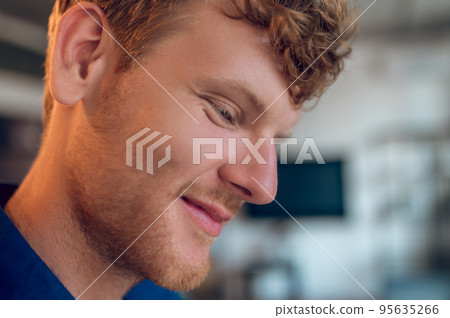 Headshot of a ginger young man looking down and smiling Headshot of a ginger young man looking down and smiling 95635266