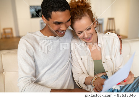 Two young people sitting on the sofa and choosing something online Two young people sitting on the sofa and choosing something online 95635340