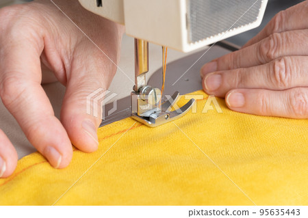 Hands of seamstress sewing with a professional machine. Concept of Factory, Home Hands of seamstress sewing with a professional machine. Concept of Factory, Home 95635443