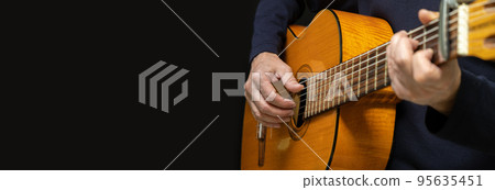 Guitarist playing acoustic guitar on black background, selective focus. Long wide banner, copy space 95635451