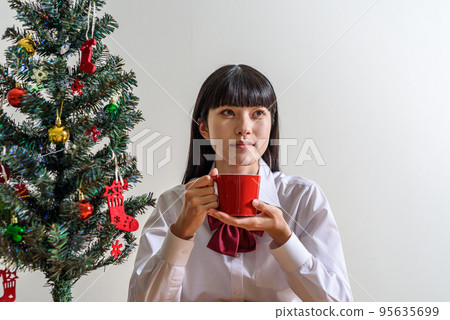 一個期待聖誕節的高中女生從杯子裡喝一杯熱身 95635699