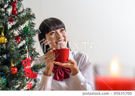 一個期待聖誕節的高中女生從杯子裡喝一杯熱身 95635700