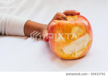 Child's hand holding a Halloween apple 95635791