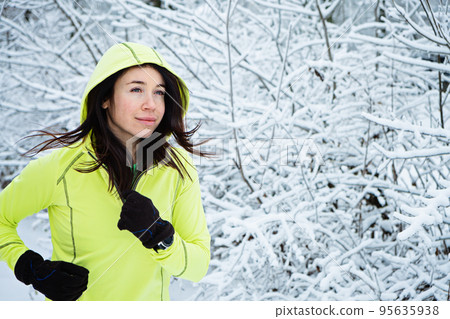 Cold Weather Running. Happy woman running in winter snowy park, forest. Running athlete woman sprinting during winter training outside in cold snow weather. 95635938