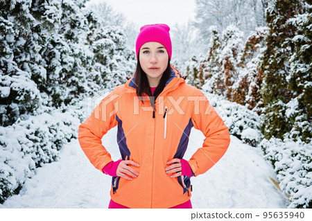 Winter workout, exercising in cold weather. Winter fitness, Safety tips for exercising outdoors. Sporty woman in sportswear standing in winter snowy park, forest. Winter workout, exercising in cold weather. Winter fitness, Safety tips for exercising outdoors. Sporty woman in sportswear standing in winter snowy park, forest. 95635940