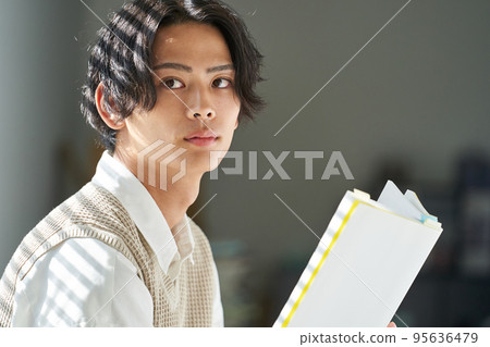 Young man reading by the window 95636479