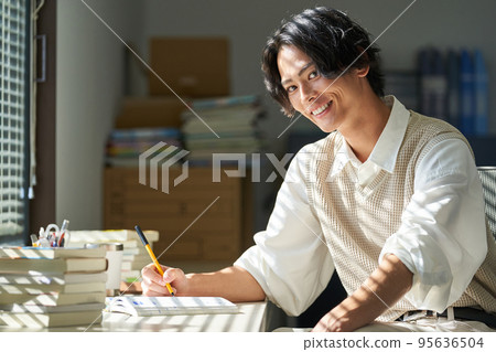 Young man studying by the window Young man studying by the window 95636504