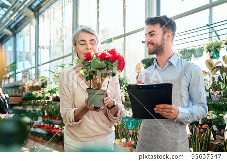 seller is a florist and a happy buyer with a plant in her hands. seller is a florist and a happy buyer with a plant in her hands. 95637547