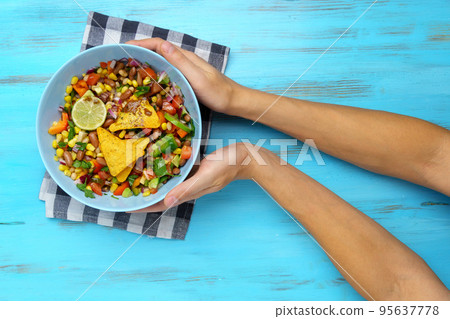 Texas caviar. Vegetable dish with corn, beans, pepper, pepper, tomatoes, beans. Served with corn chips nachos. Wooden background Texas caviar. Vegetable dish with corn, beans, pepper, pepper, tomatoes, beans. Served with corn chips nachos. Wooden background 95637778