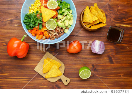 Mexican vegetable salad, cowboy caviar in bowl with ingredients and nachos. Top view Mexican vegetable salad, cowboy caviar in bowl with ingredients and nachos. Top view 95637784