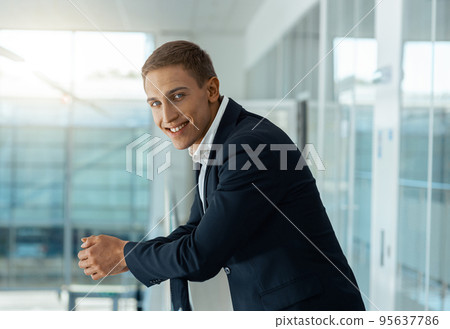 Young male businessman standing in auto show office and looking at camera. Blurred background Young male businessman standing in auto show office and looking at camera. Blurred background 95637786