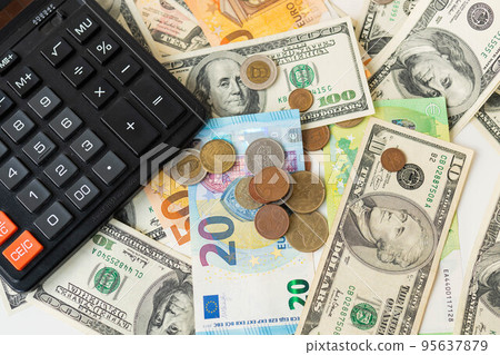 Calculator, euro and dollar banknotes, coins. Tax time, bill payment, calculator for counting. 95637879