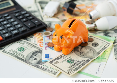 Piggy piggy bank of orange color soit on curry. Calculator, euro and dollar banknotes, coins. Tax time, bill payment, calculator for counting. Piggy piggy bank of orange color soit on curry. Calculator, euro and dollar banknotes, coins. Tax time, bill payment, calculator for counting. 95637889