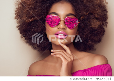 Beautiful portrait of an African girl in sunglasses in the shape of hearts Beautiful portrait of an African girl in sunglasses in the shape of hearts 95638041