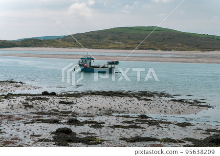 A small fishing boat moored near the shore at low tide. Seaside landscape. Sea. 95638209
