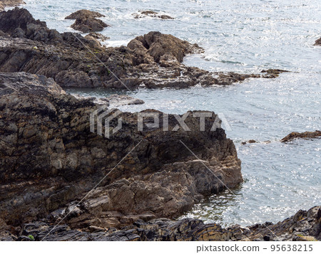 Exposed rocks on the shore. Seaside in sunny weather, rock formation near body of water. 95638215