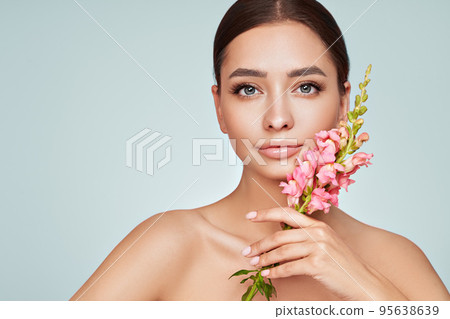 Beautiful young woman with a pink larkspur flower Beautiful young woman with a pink larkspur flower 95638639
