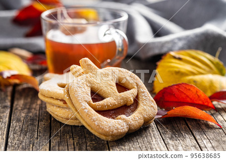Linzer cookies in the shape of a Halloween pumpkin on wooden table. Linzer cookies in the shape of a Halloween pumpkin on wooden table. 95638685
