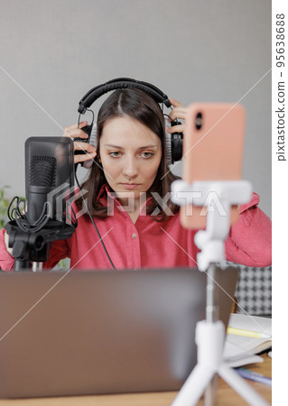 woman in a home office records podcast audio content with a microphone and headphones and a labrador dog woman in a home office records podcast audio content with a microphone and headphones and a labrador dog 95638688