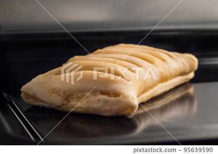 Uncooked homemade bun with ham, cheese on tray in electric oven: close up Uncooked homemade bun with ham, cheese on tray in electric oven: close up 95639590