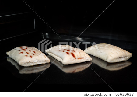 Three uncooked homemade buns with red strawberry jam on tray in electric oven Three uncooked homemade buns with red strawberry jam on tray in electric oven 95639638