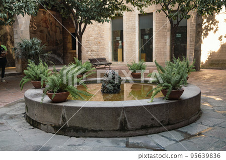 Valencia, Spain. Beautiful view of a cozy court with fountain in old town. Cityscape, Fountain with huge bowl in shady landscaped park for relaxation and walks. 95639836