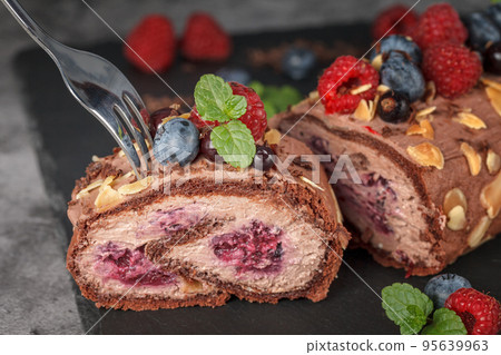 Meringue roll with raspberry berries, pigeons and mint leaves Meringue roll with raspberry berries, pigeons and mint leaves 95639963