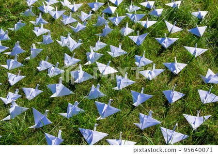Japanese folded Origami cranes on fresh grass. Hundreds handmade paper birds on green field with copy space. 1000 thousand crane tsuru sculpture topic. Symbol of peace, health, wishes and hope 95640071