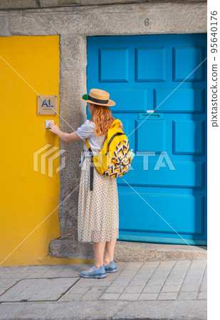 Tourist woman ringing on doorbell at the AL entrance in Portugal town Tourist woman ringing on doorbell at the AL entrance in Portugal town 95640176