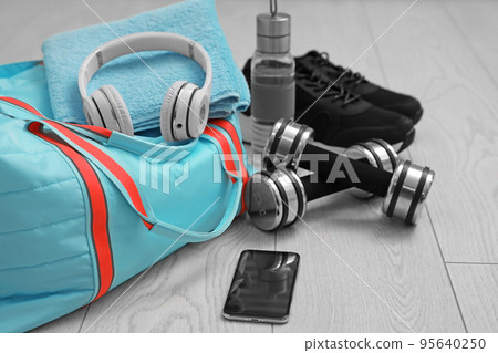 Sports bag and gym stuff on wooden floor 95640250