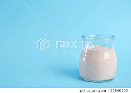Tasty organic yogurt on light blue background. Space for text 95640303