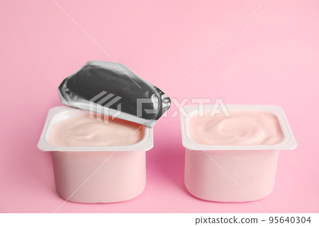Tasty organic yogurt in plastic cups on pink background 95640304