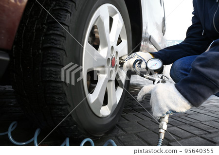 Mechanic checking tire air pressure at car service, closeup 95640355