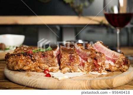 Delicious grilled ribs served on wooden table indoors, closeup 95640418