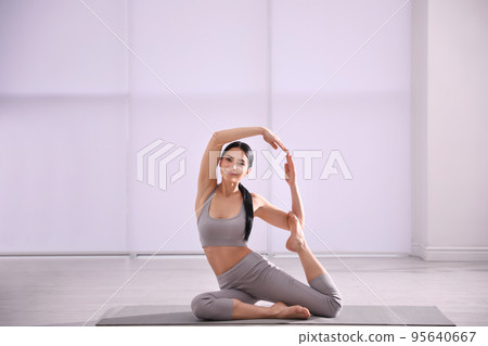 Young woman practicing mermaid asana in yoga studio. Eka Pada Rajakapotasana pose Young woman practicing mermaid asana in yoga studio. Eka Pada Rajakapotasana pose 95640667