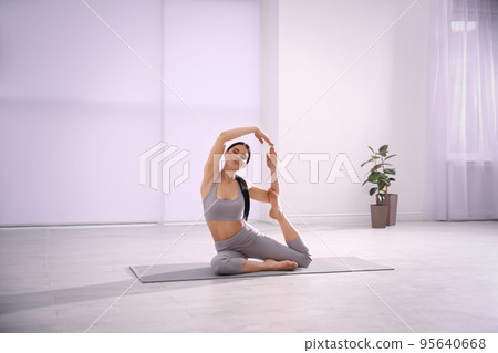 Young woman practicing mermaid asana in yoga studio. Eka Pada Rajakapotasana pose 95640668