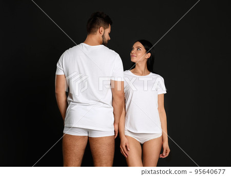 Young couple in white t-shirts and underwear on black background 95640677