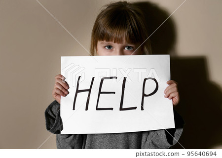 Abused little girl showing with phrase HELP ME near blue wall, focus on hand. 95640694