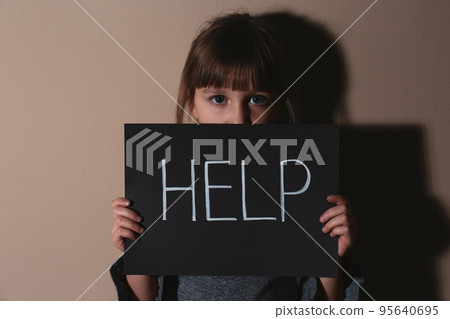 Abused little girl showing with phrase HELP ME near blue wall, focus on hand. Abused little girl showing with phrase HELP ME near blue wall, focus on hand. 95640695