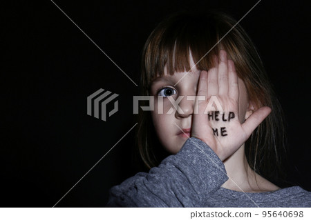 Abused little girl showing with phrase HELP ME near blue wall, focus on hand. Abused little girl showing with phrase HELP ME near blue wall, focus on hand. 95640698