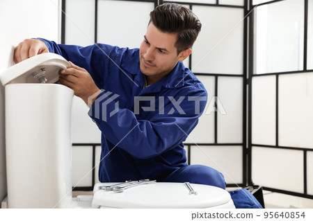 Professional plumber working with toilet bowl in bathroom Professional plumber working with toilet bowl in bathroom 95640854