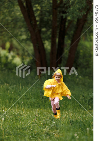 Happy funny baby under autumn shower. Girl running merrily laughing in the rain 95640875