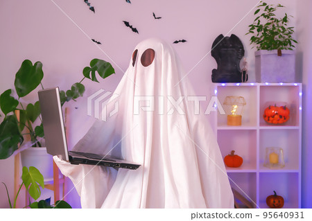 The ghost of Halloween uses a laptop to surf the The ghost of Halloween uses a laptop to surf the 95640931