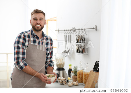 Young man holding bowl of tasty cream soup in kitchen Young man holding bowl of tasty cream soup in kitchen 95641092