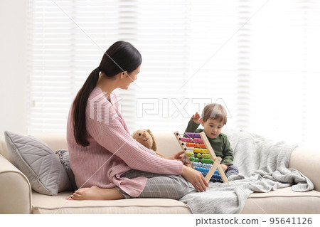 Young nanny and cute little baby playing with abacus at home 95641126