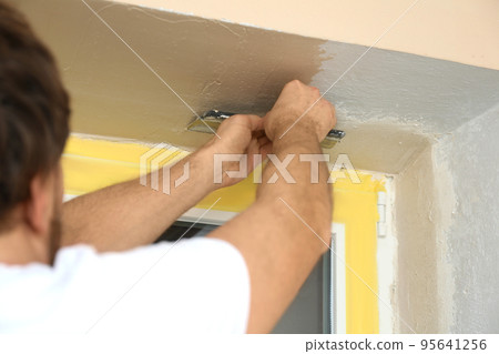 Man plastering window area with putty knife indoors, closeup. Interior repair Man plastering window area with putty knife indoors, closeup. Interior repair 95641256