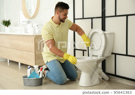 Young man cleaning toilet bowl in bathroom Young man cleaning toilet bowl in bathroom 95641363